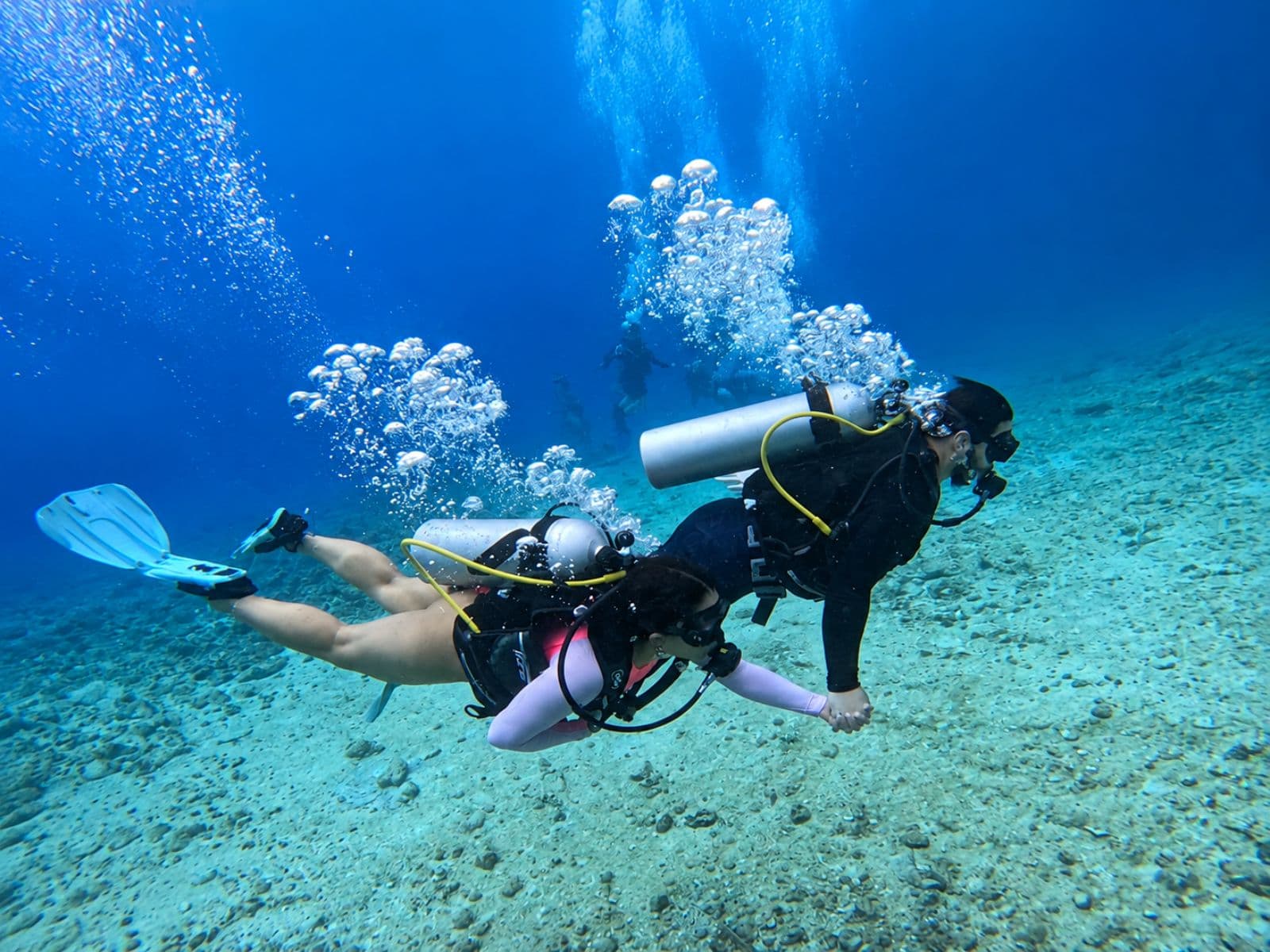 Scuba diving over the white sandy bottom, with a trail of bubbles