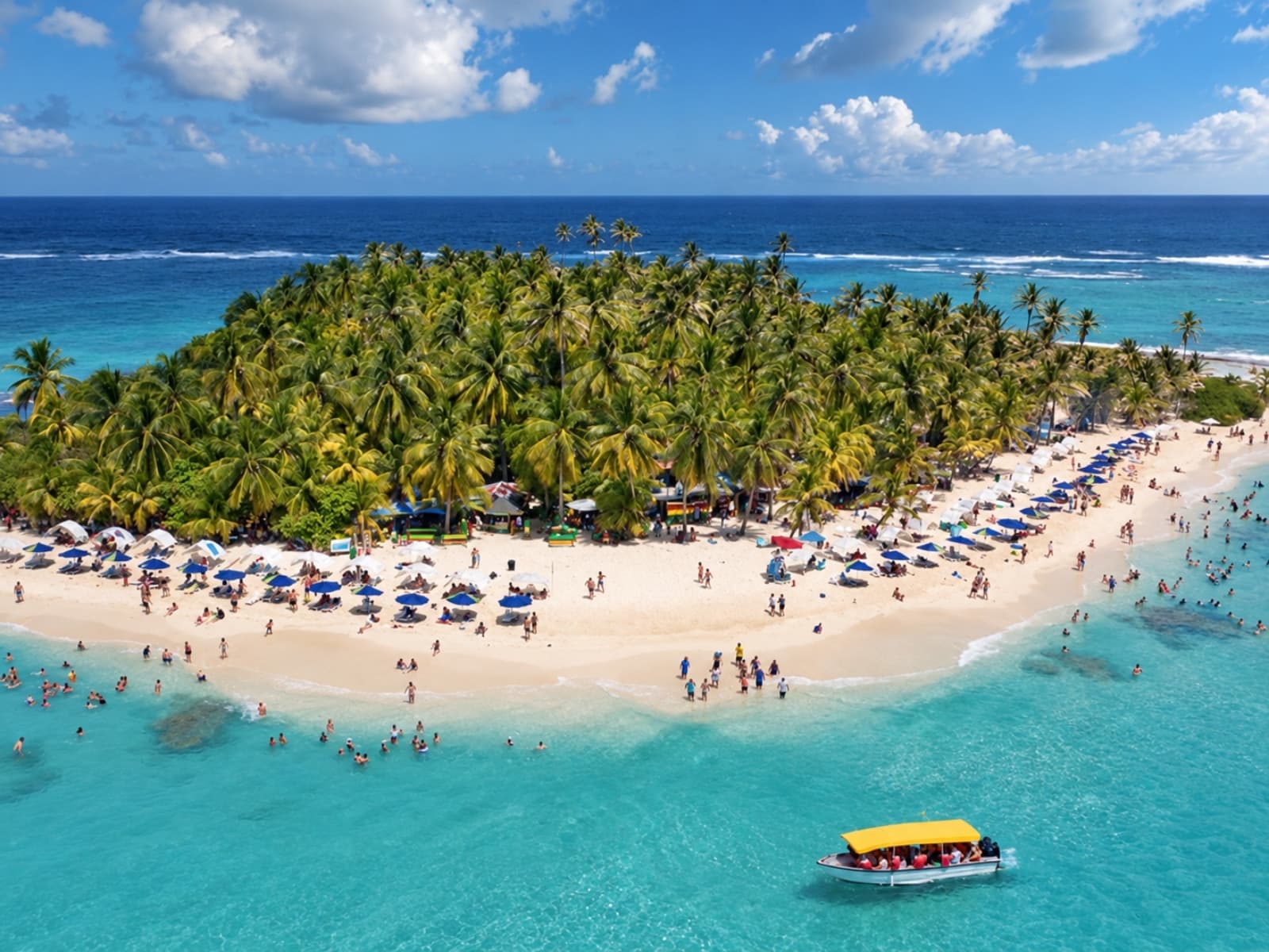 Aerial view of Johnny Cay: the cay covered in palm trees, the white-sand beach with umbrellas and beachgoers, and a yellow-roofed boat in the turquoise water