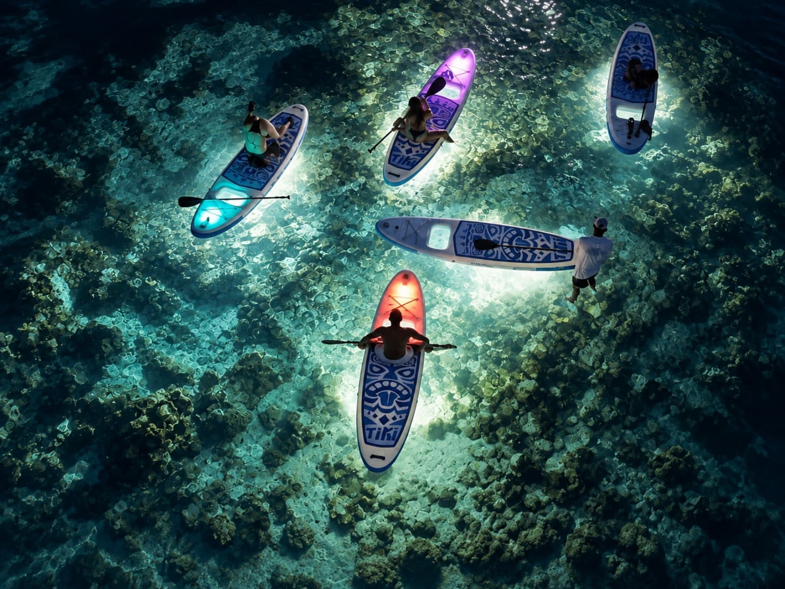 Aerial view of five boards whose LED lights illuminate the reef at night