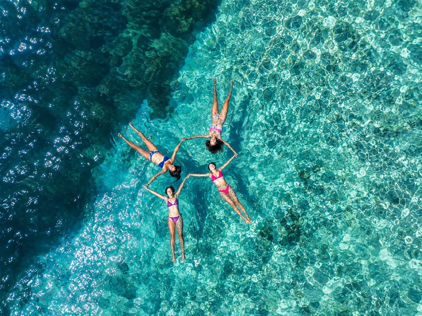 Aerial view of travelers floating in a circle in the turquoise water
