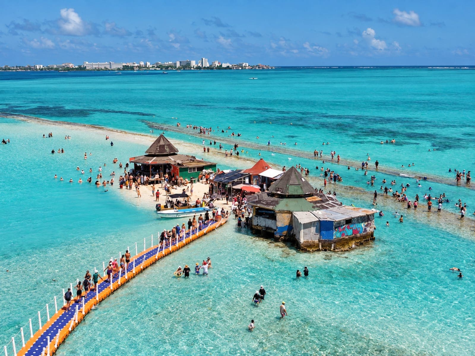 Aerial view of the Aquarium: the floating bridge, the kiosks on the sandbank and the swimmers in the turquoise water; in the background, the island of San Andrés